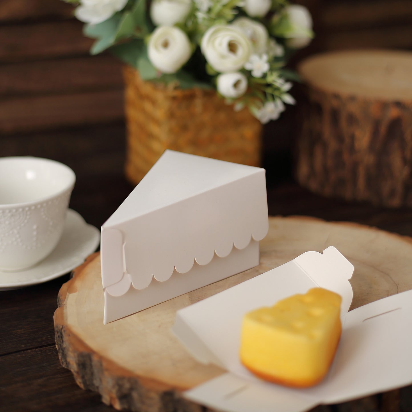 White triangular paper cake box with scalloped top, displayed with a dessert.