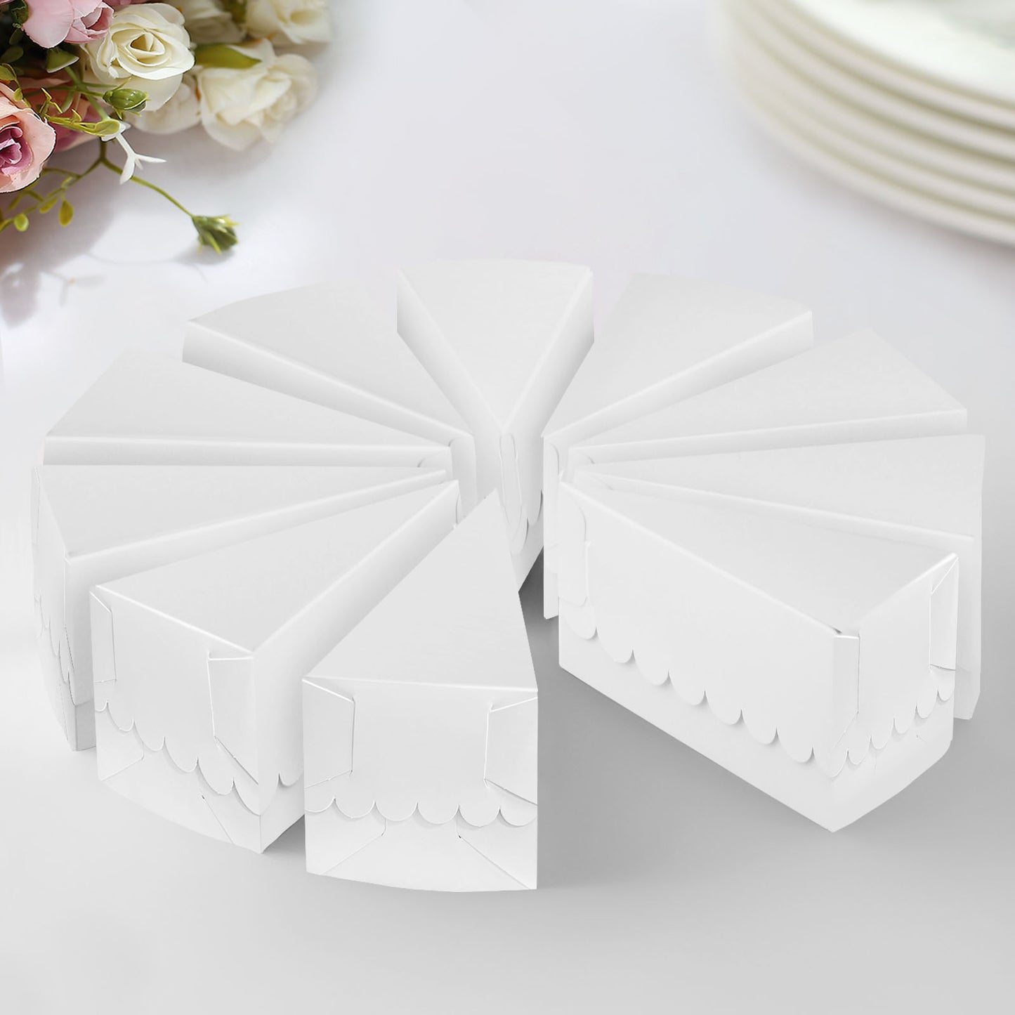 White triangular paper cake boxes with scalloped tops, arranged in a circle.