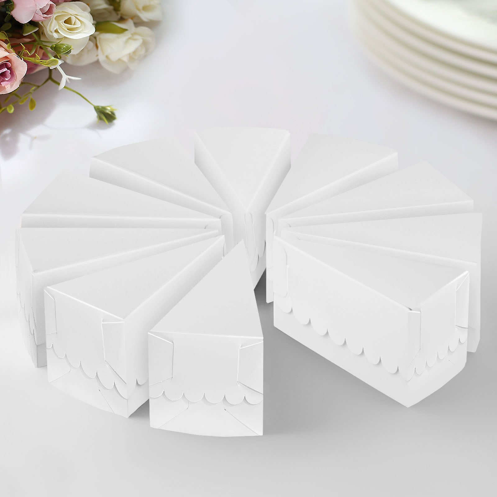 White triangular paper cake boxes with scalloped tops, arranged in a circle.