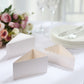 White triangular paper cake boxes with scalloped tops on a table.
