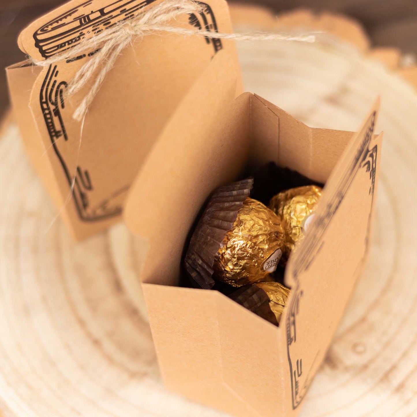 Natural mini mason jar-shaped favor boxes with jute rope ties, filled with candy.