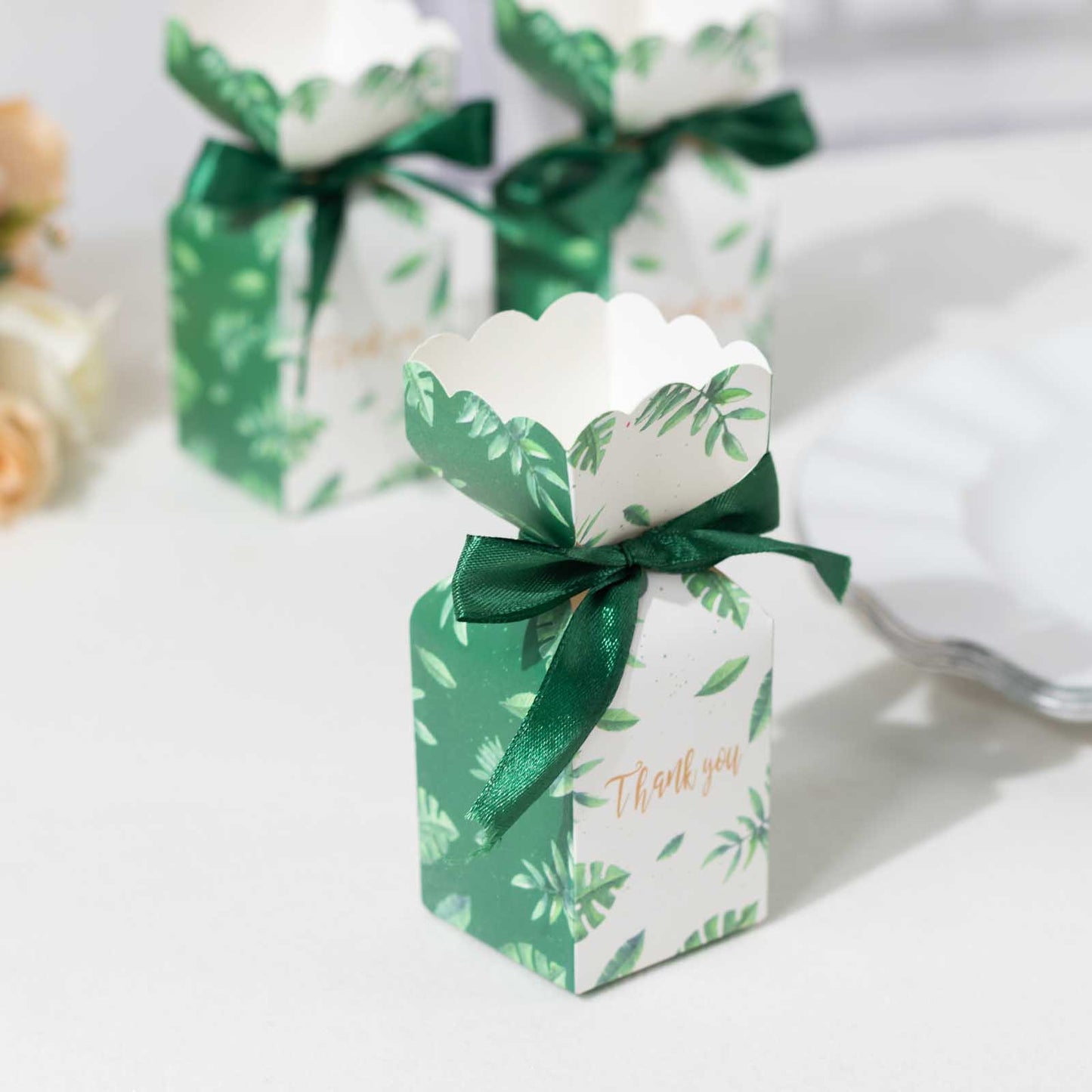 White and green leaf print satin ribbon gift boxes with floral tops.