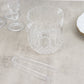 Clear plastic ice bucket with tongs in crystal-cut design for drinks.