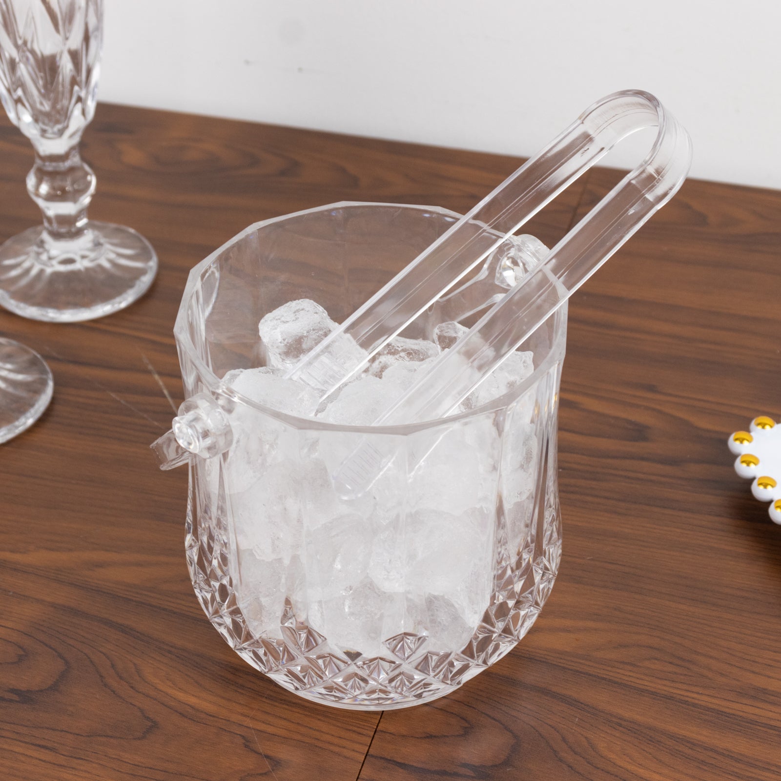 Clear plastic ice bucket with handle and tongs, shatterproof design.