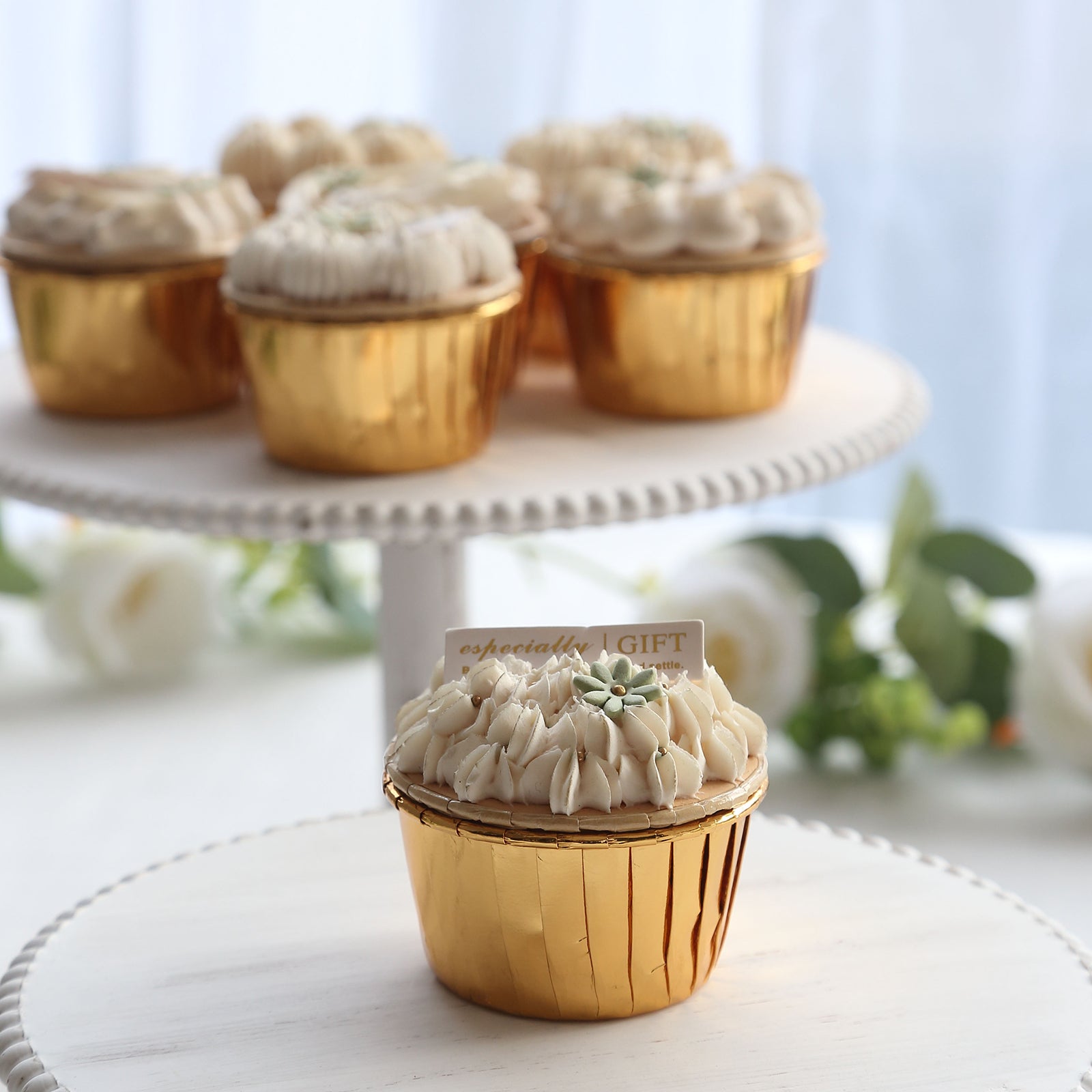 Metallic gold foil baking cups with dessert cupcakes on a tiered stand.