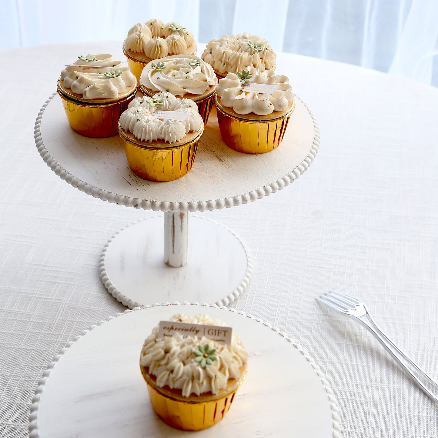 Metallic gold foil baking cups with desserts on a white stand.