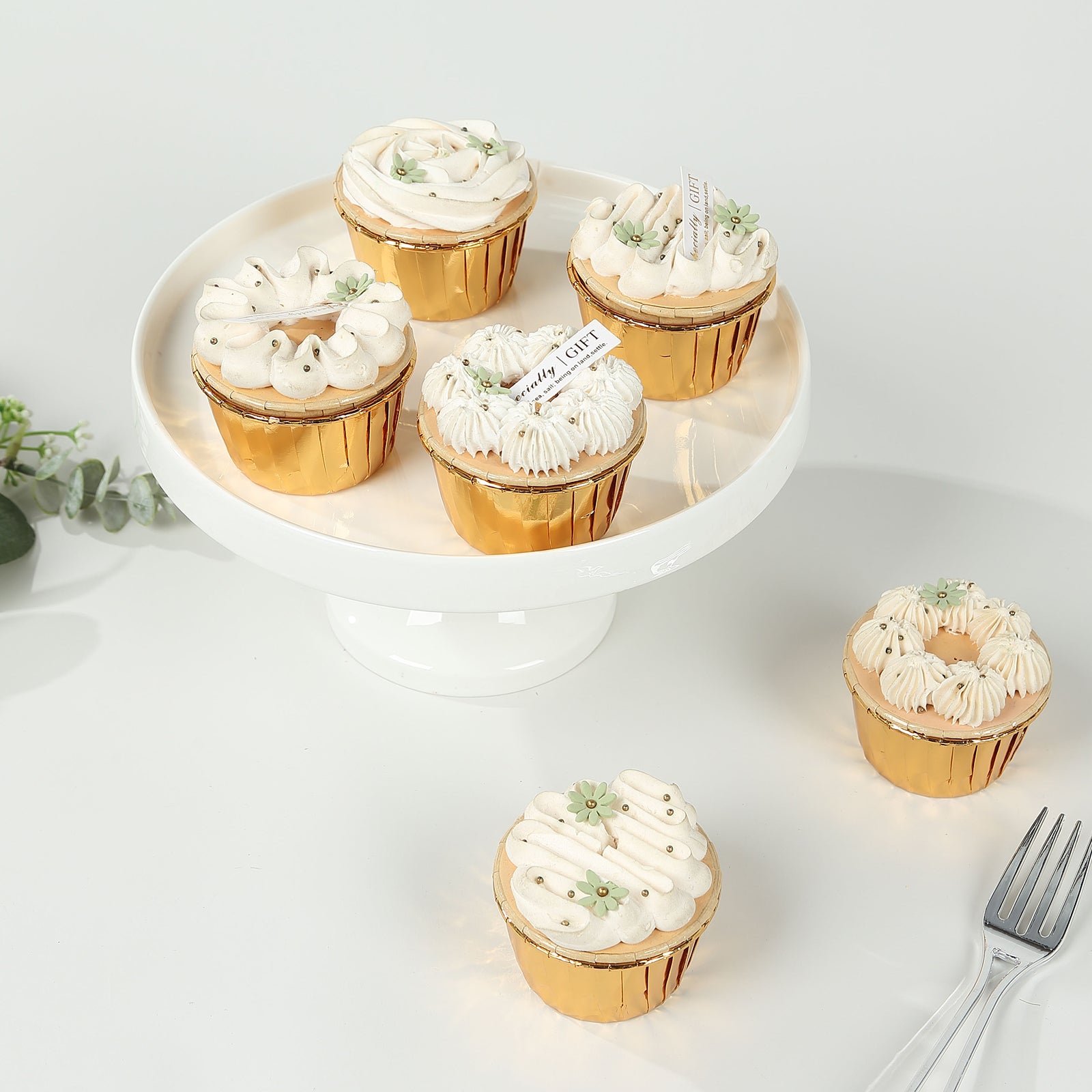 Metallic gold foil baking cups with desserts on a white serving platter.