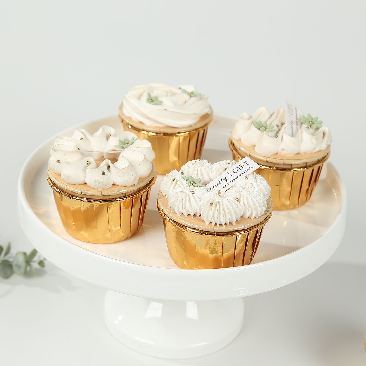 Metallic gold foil baking cups with desserts on a white pedestal.
