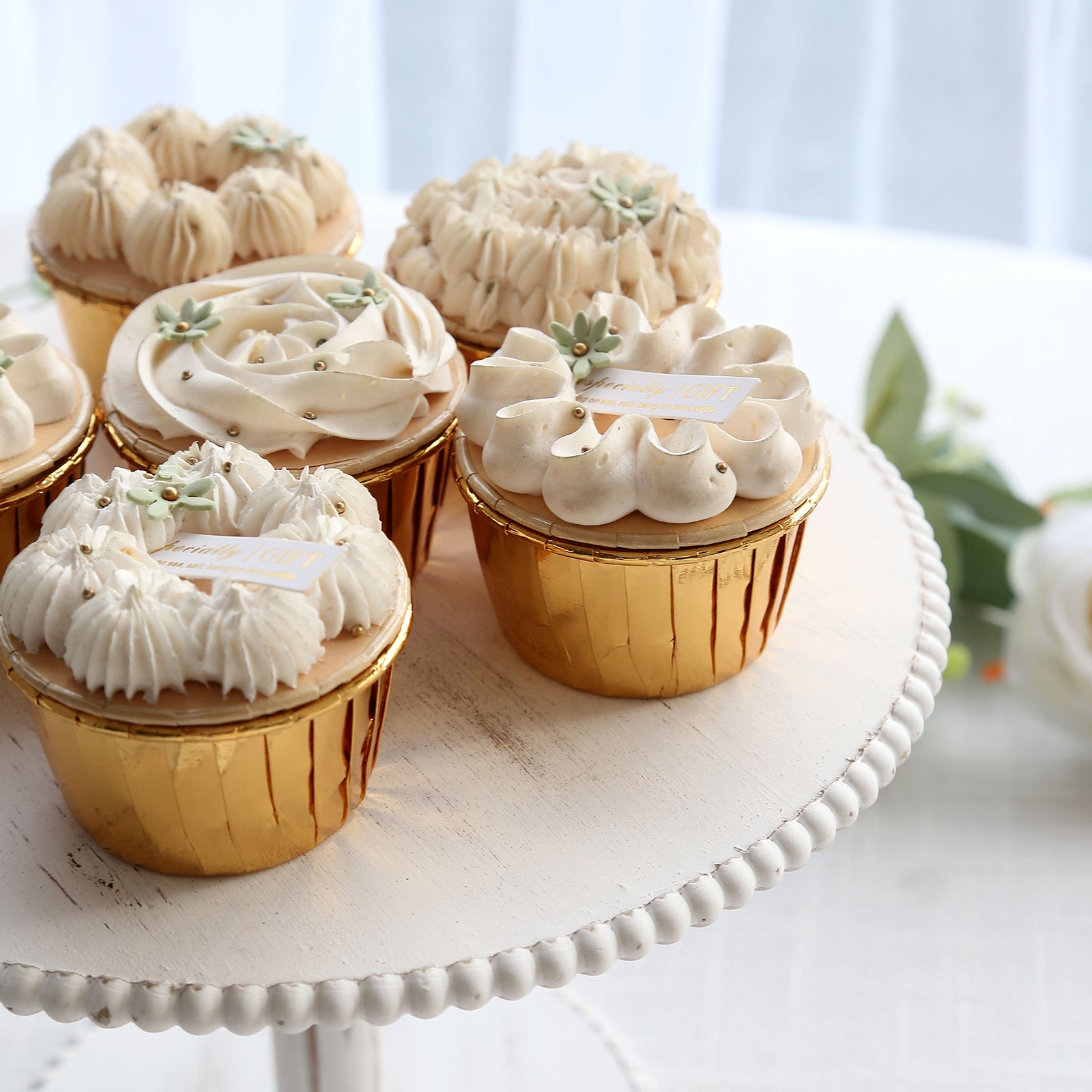 Metallic gold foil baking cups with cream frosting cupcakes.