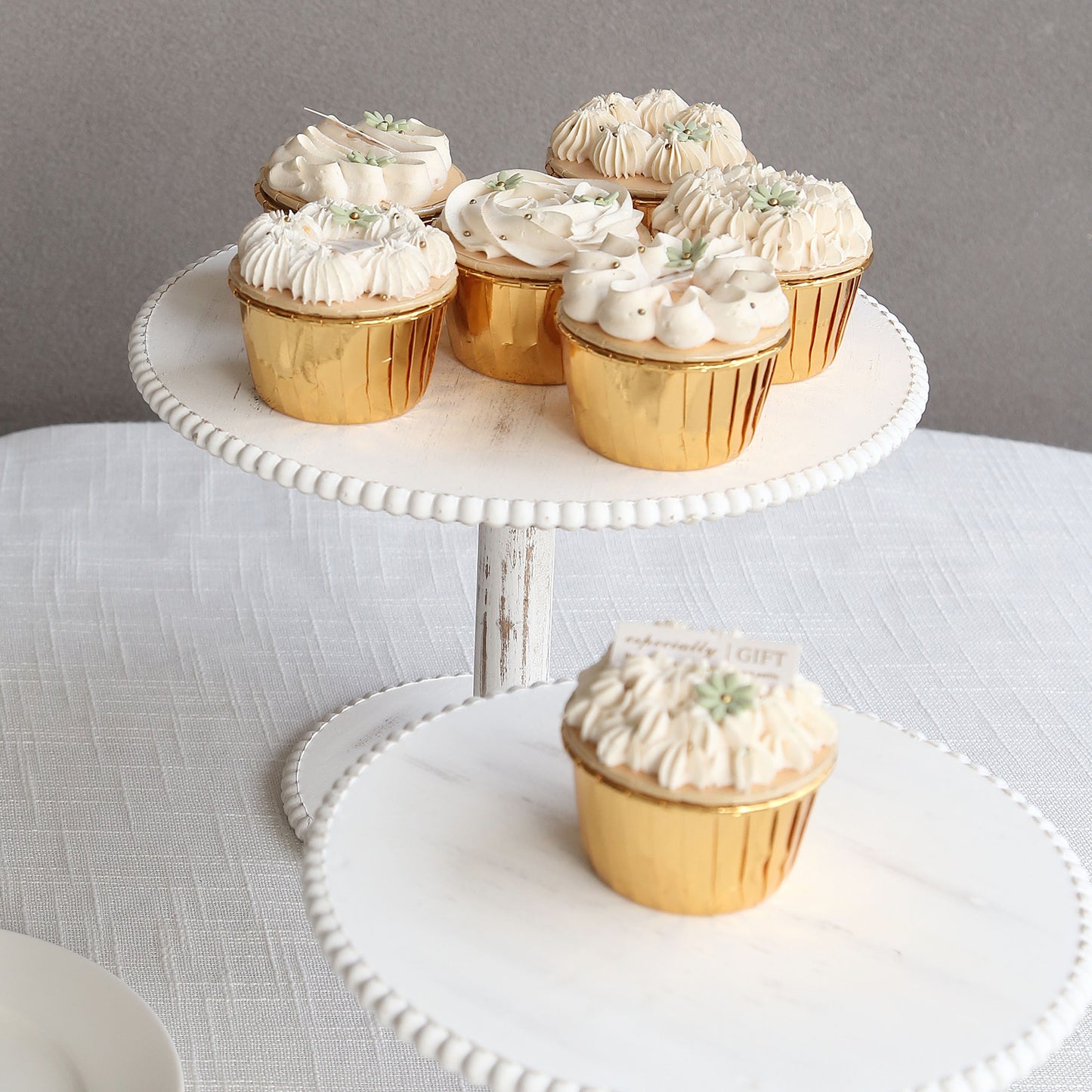 Metallic gold foil baking cups with desserts on a white cake stand.