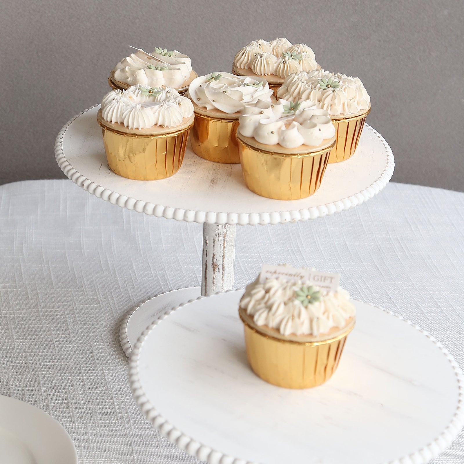 Metallic gold foil baking cups with desserts on a white cake stand.