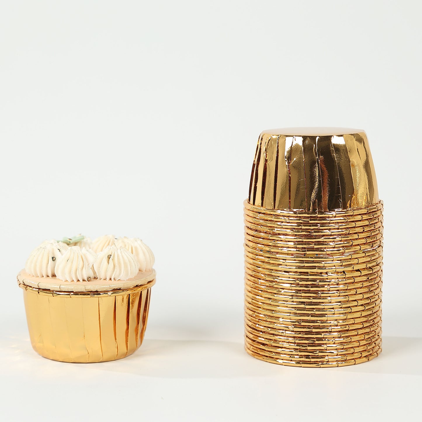 Metallic gold foil baking cups stacked with a cupcake on the side.