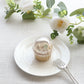 Clear disposable dome lid on a cupcake, surrounded by decorative flowers.