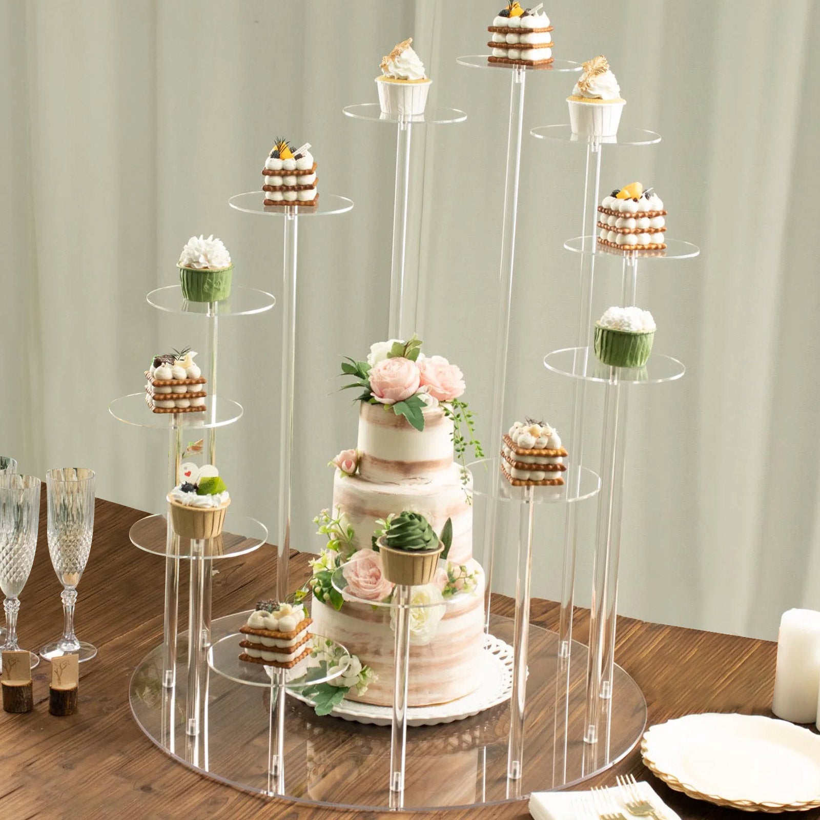 Clear acrylic 12-arm dessert display stand with cupcakes and a cake.