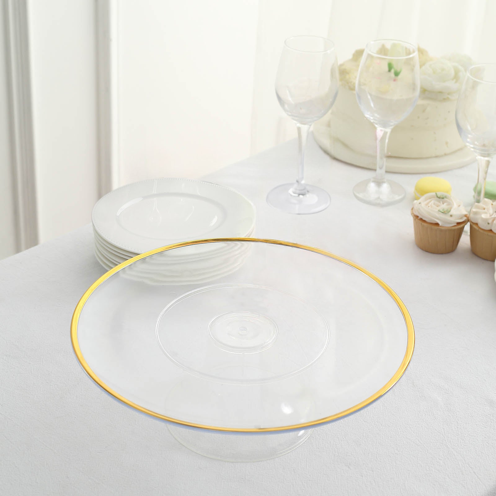 Clear cupcake display riser with gold rim on a table setting.