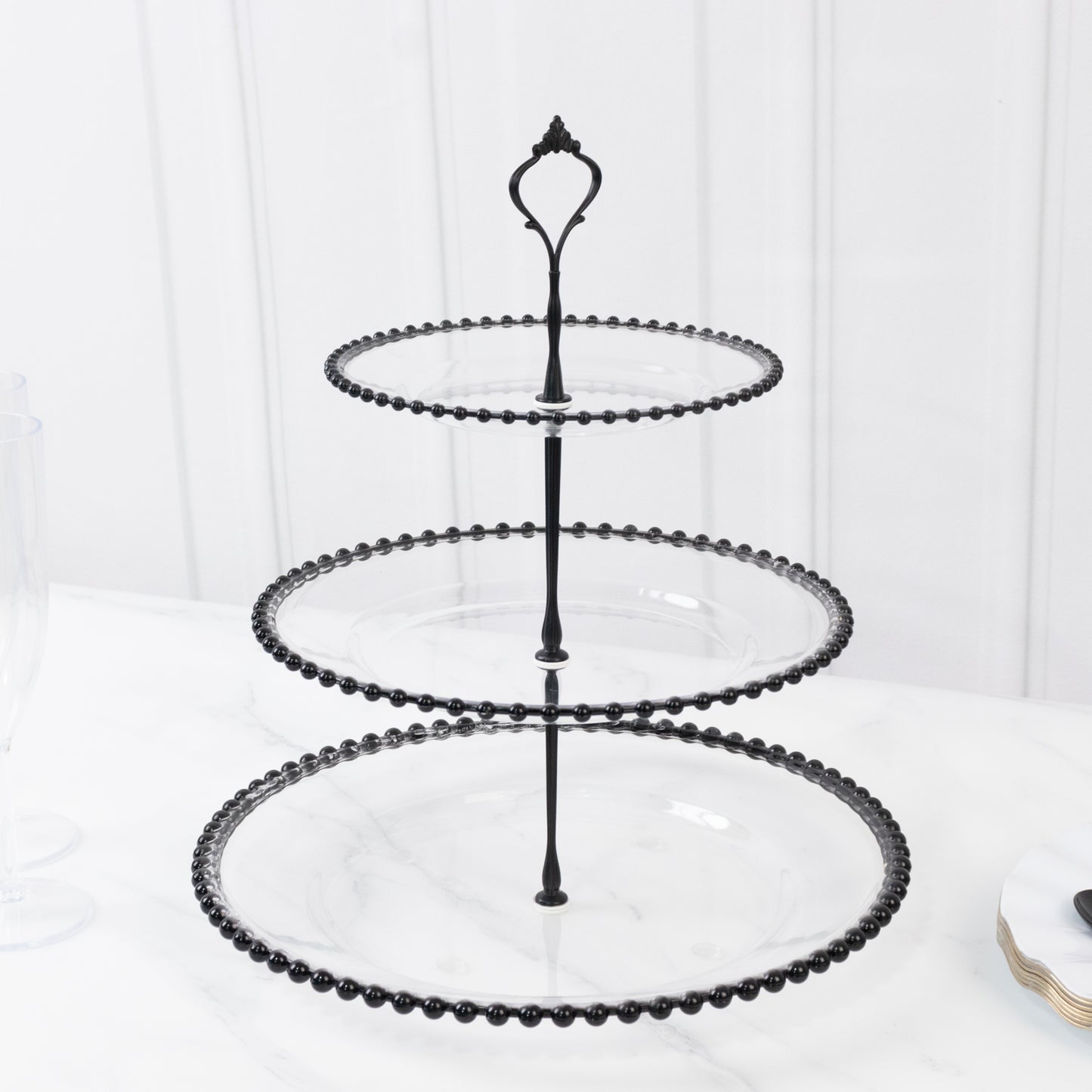 Clear 3-tier dessert stand with black beaded rim and top handle.