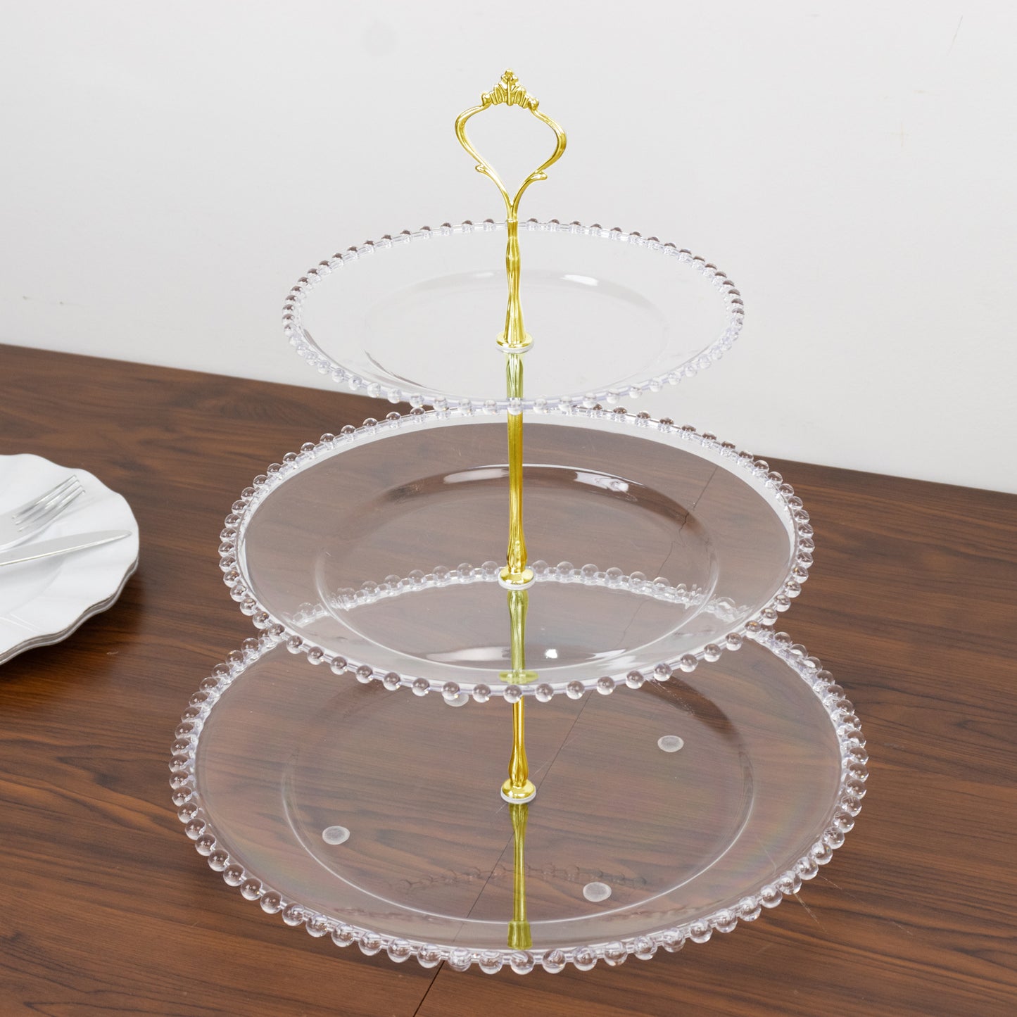 Clear 3-tier plastic dessert display stand with beaded rim and top handle.