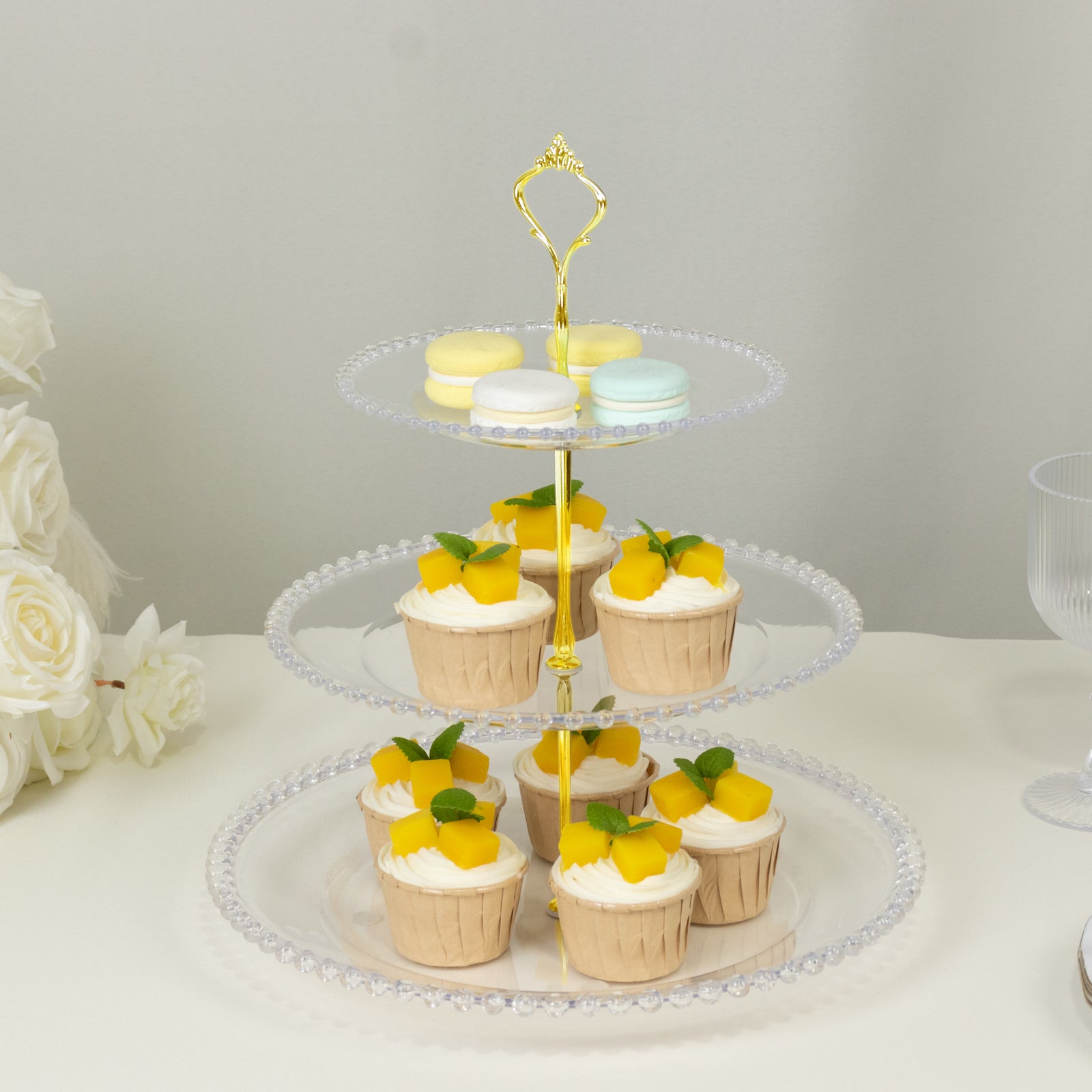 Clear 3-tier dessert display stand with cupcakes and macaroons, perfect for tea parties.