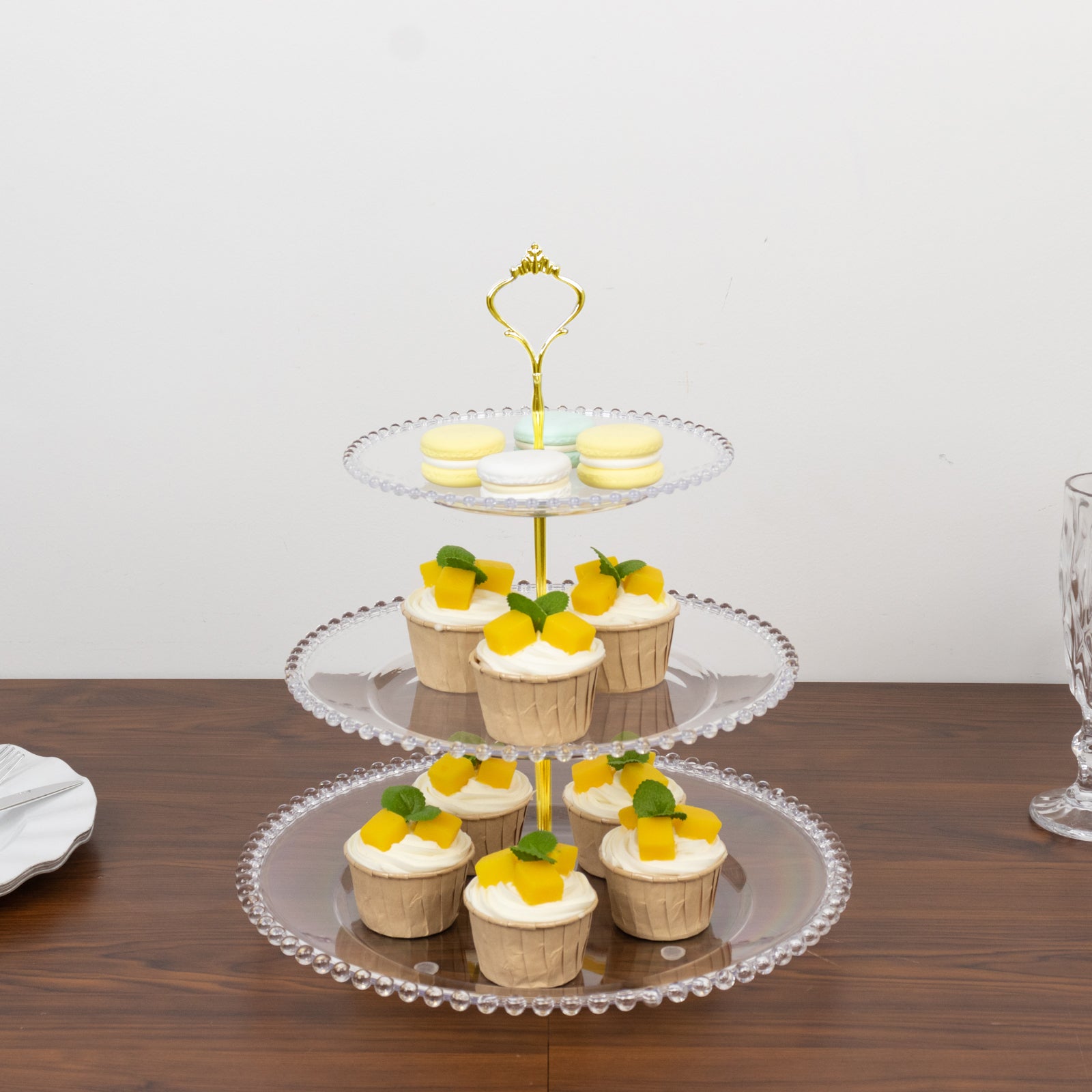 Clear 3-tier dessert display stand with cupcakes and beaded rim.