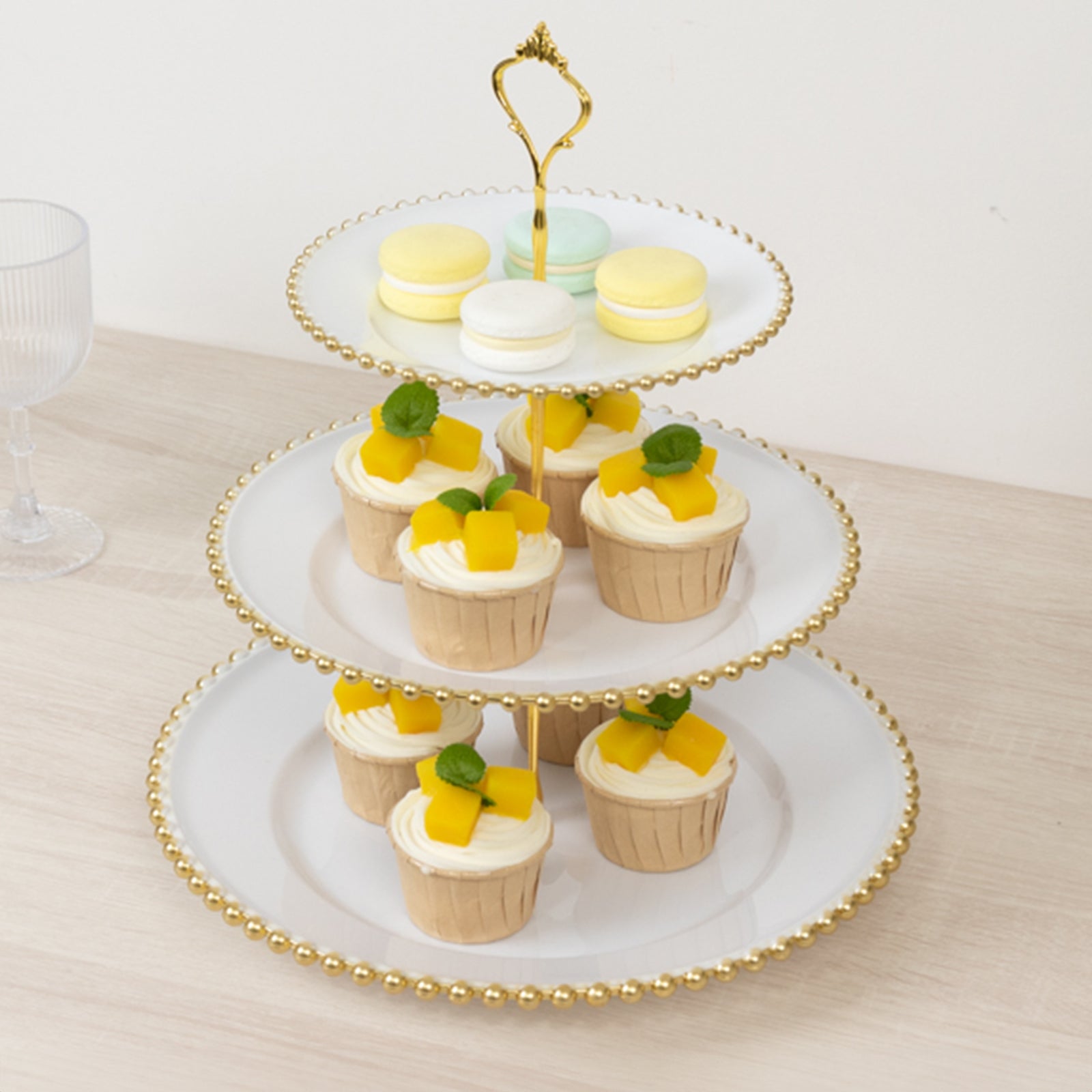 White 3-tier dessert display stand with gold beaded rim and cupcakes.