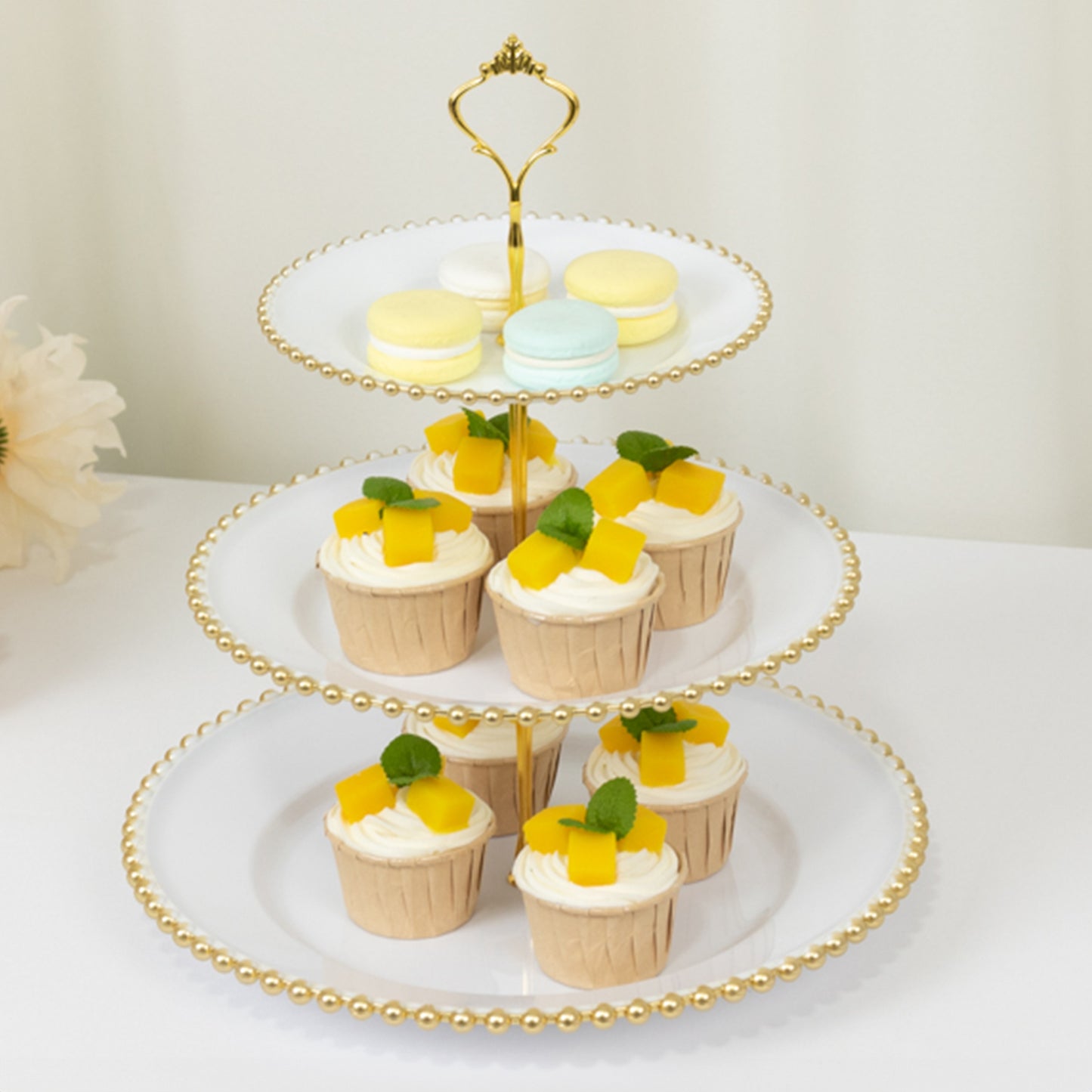White 3-tier dessert display stand with gold beaded rim and colorful treats.