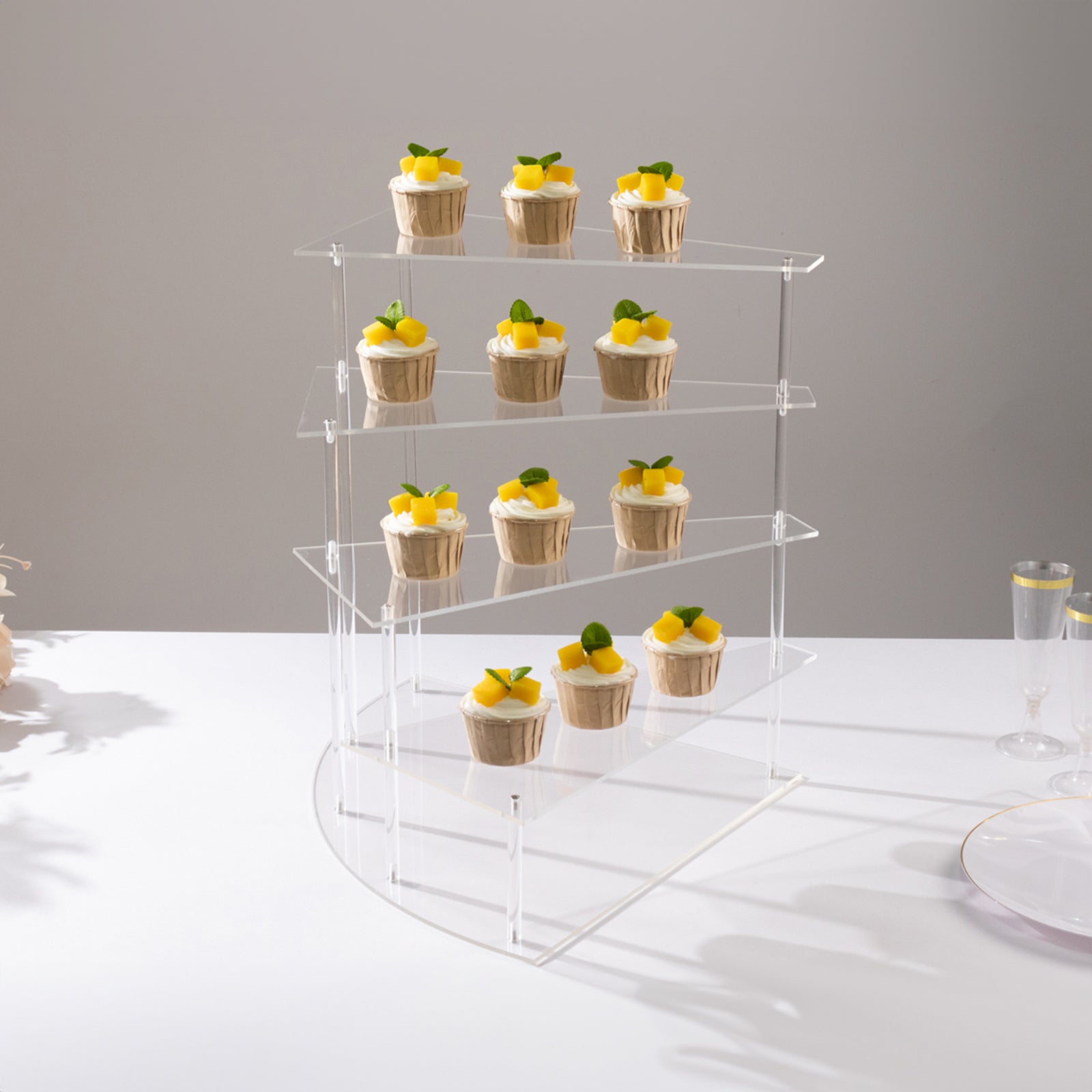 Clear acrylic 4-tier cupcake stand displaying desserts.