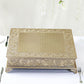 Gold embossed cake pedestal on a white tablecloth.