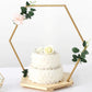 Gold hexagon floral hoop cake stand with wooden base and white floral decoration.