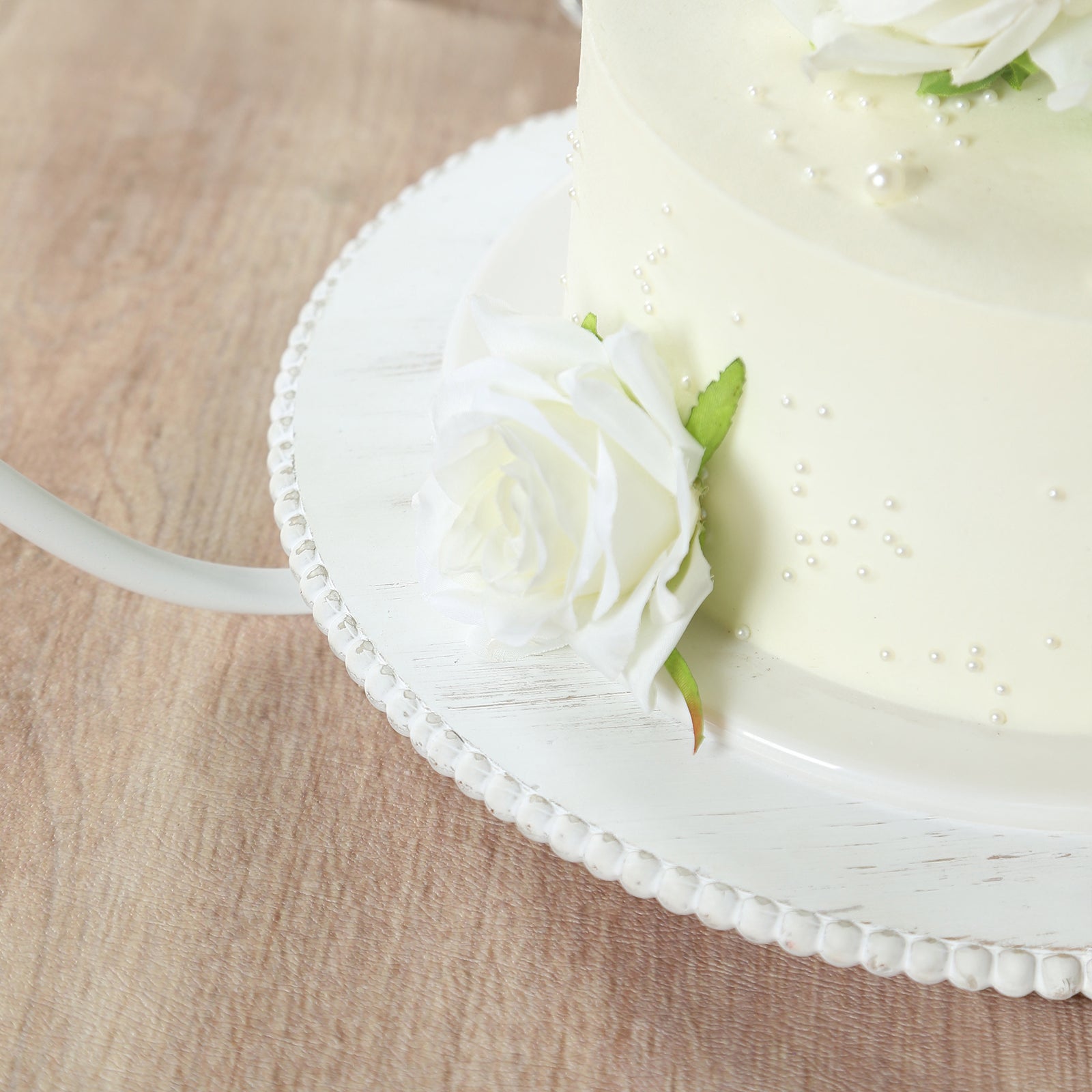 Whitewash metal floral hoop cake stand with beaded wooden base.