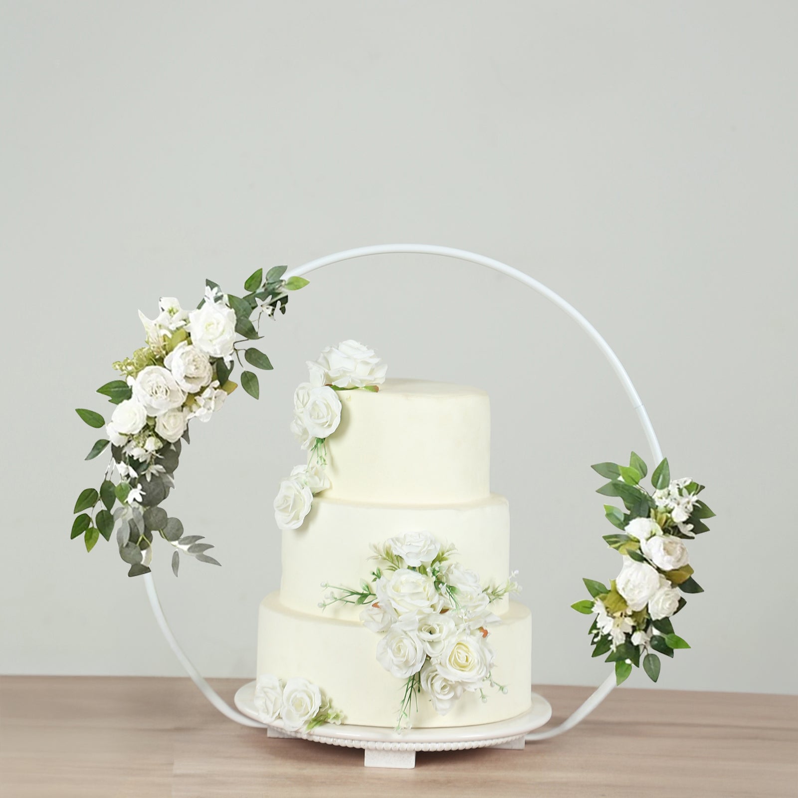 Whitewashed metal floral hoop cake stand with a beaded wooden base.