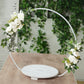 White floral hoop cake stand with beaded wooden base and greenery.