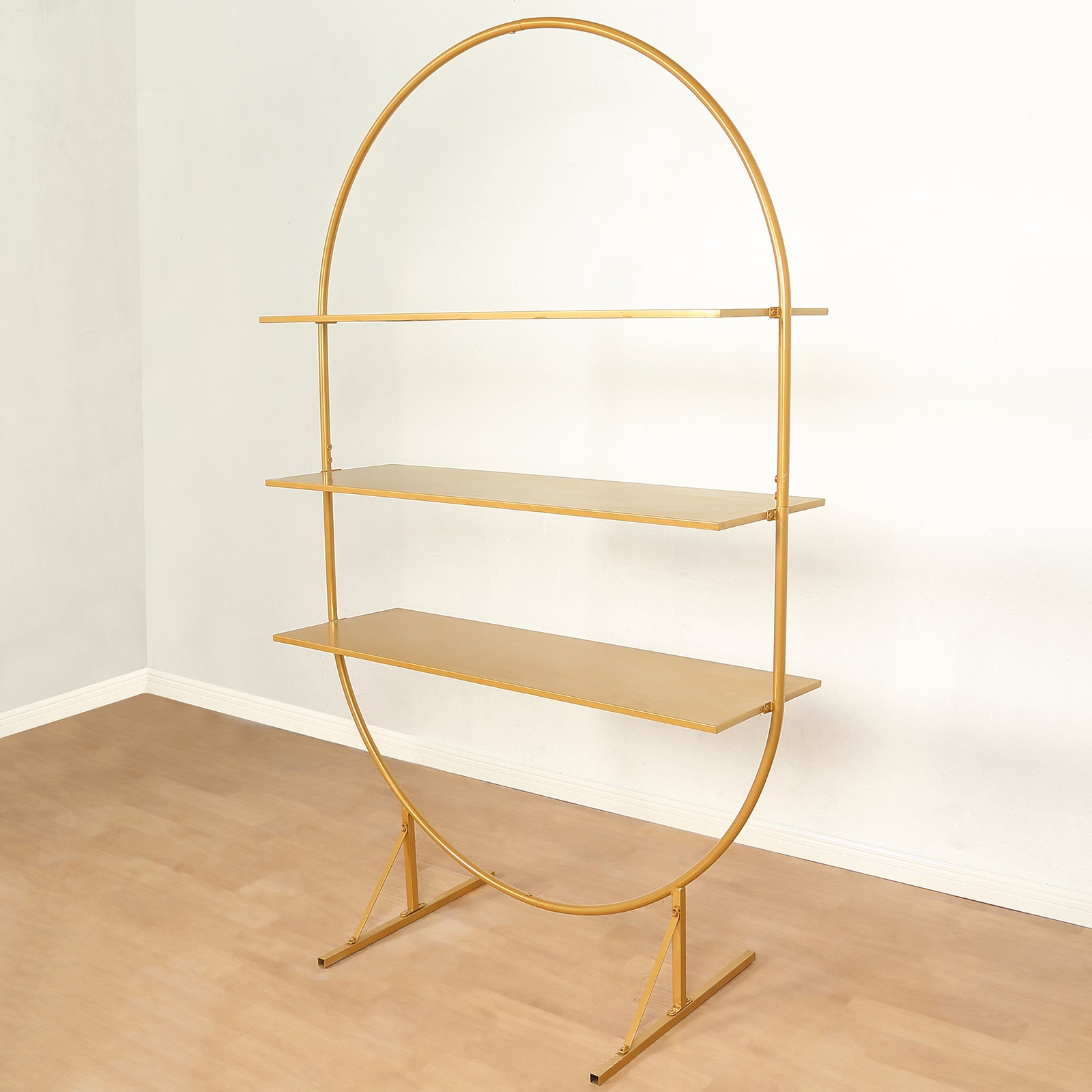 6.5ft gold metal arch cake display stand with three tiers and oval shelves.