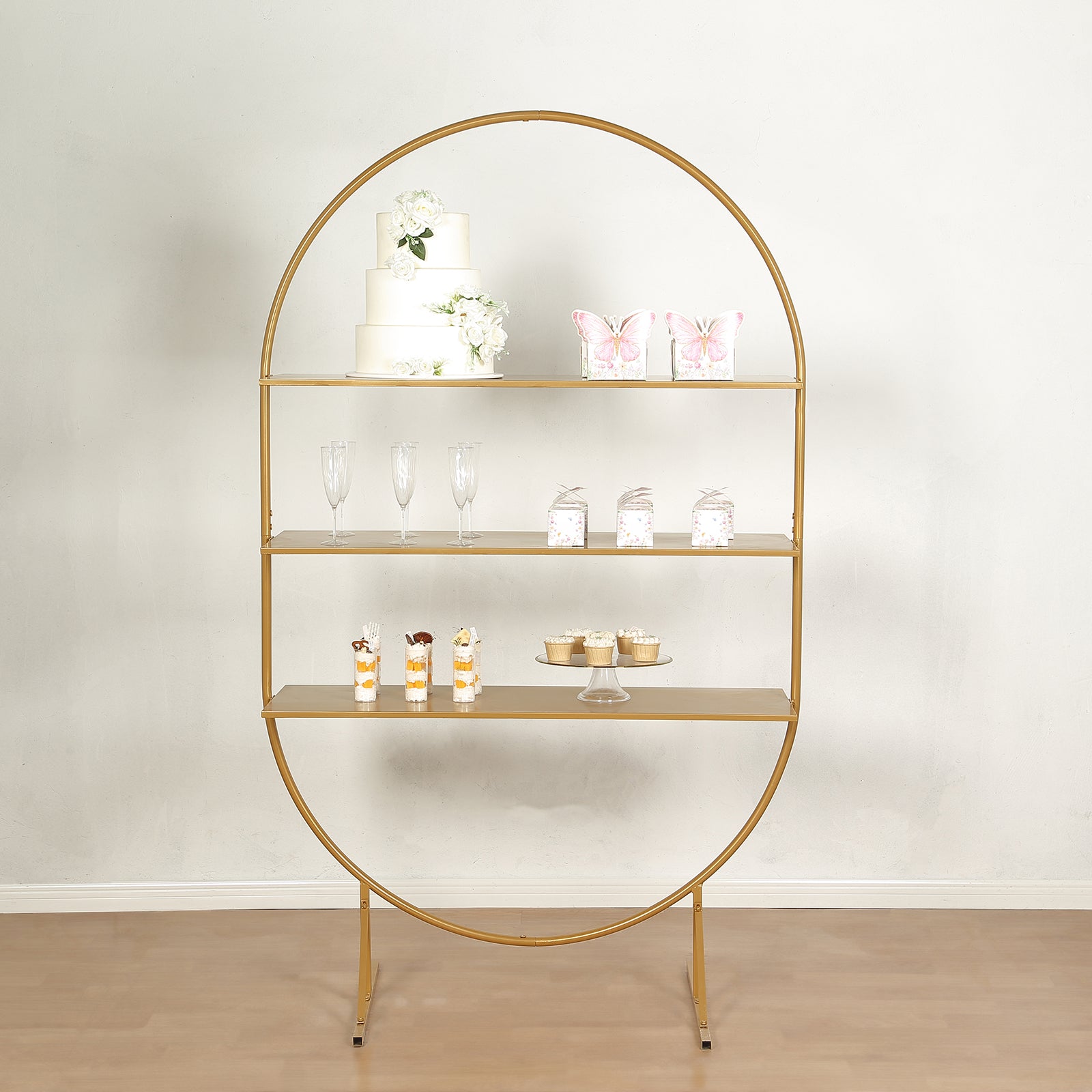 Gold metal arch cake display stand with three tiers for desserts and cupcakes.