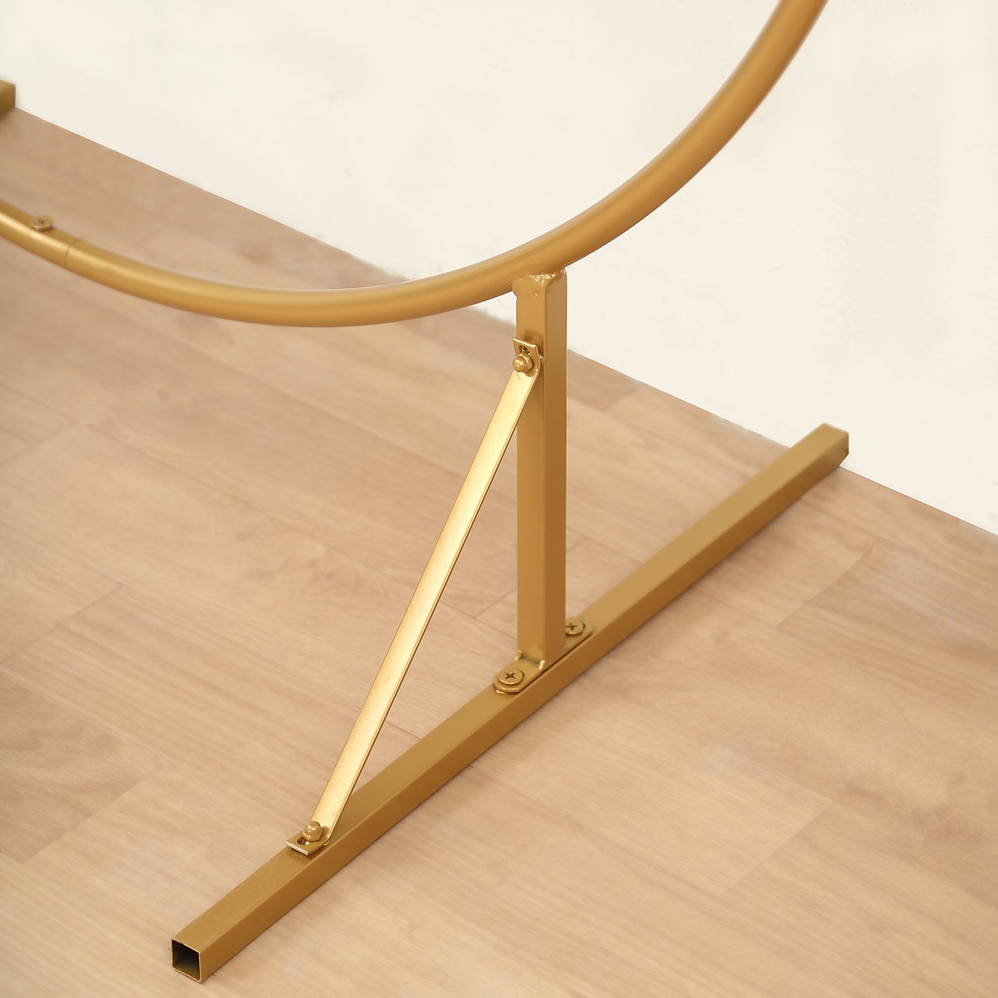 Gold metal cake display stand base on a wooden floor.
