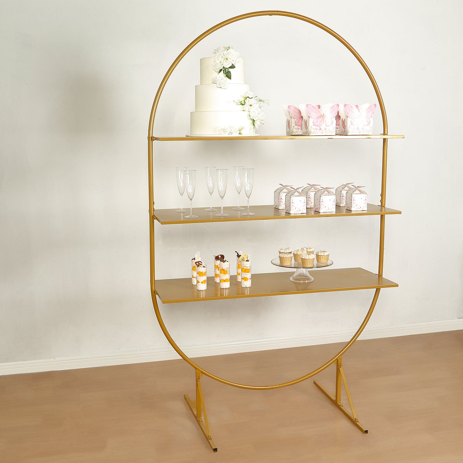 Gold metal arch cake display stand with three tiers for desserts and cupcakes.