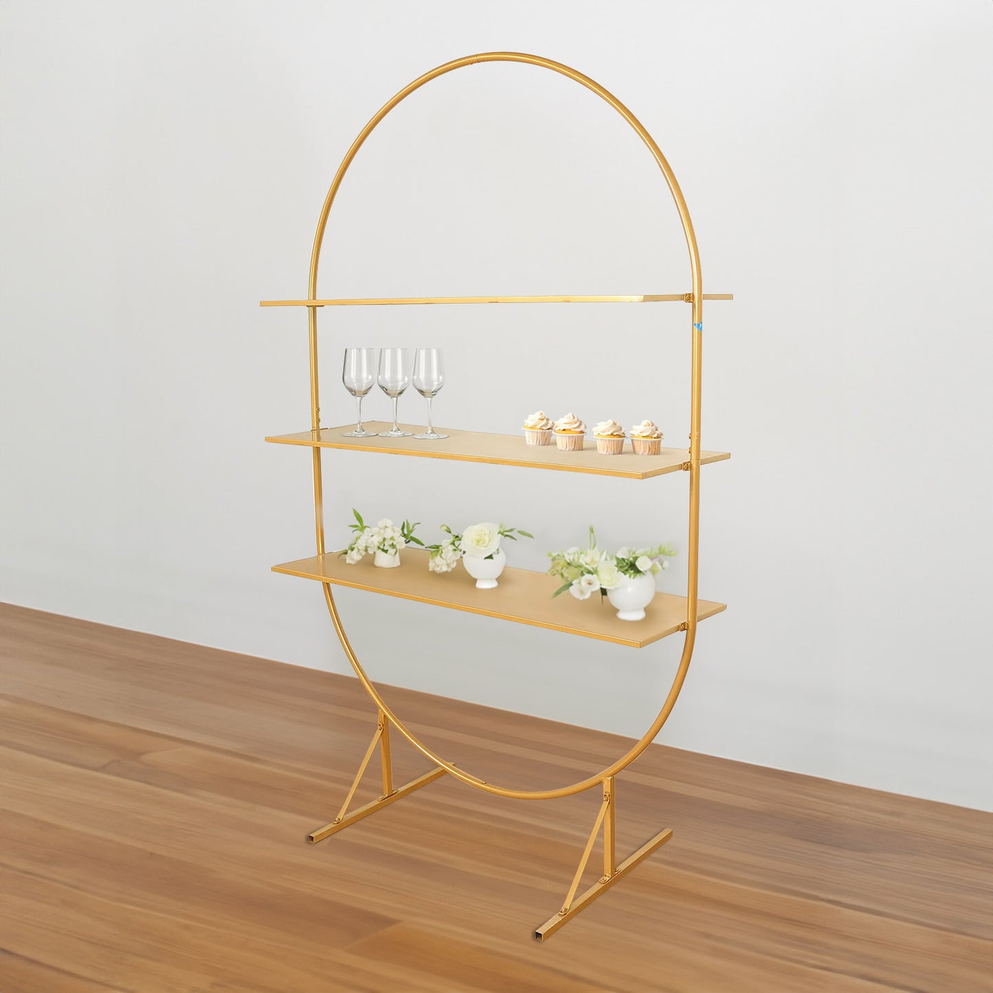 Gold 3-tier metal arch cake display stand with cupcakes and flowers.