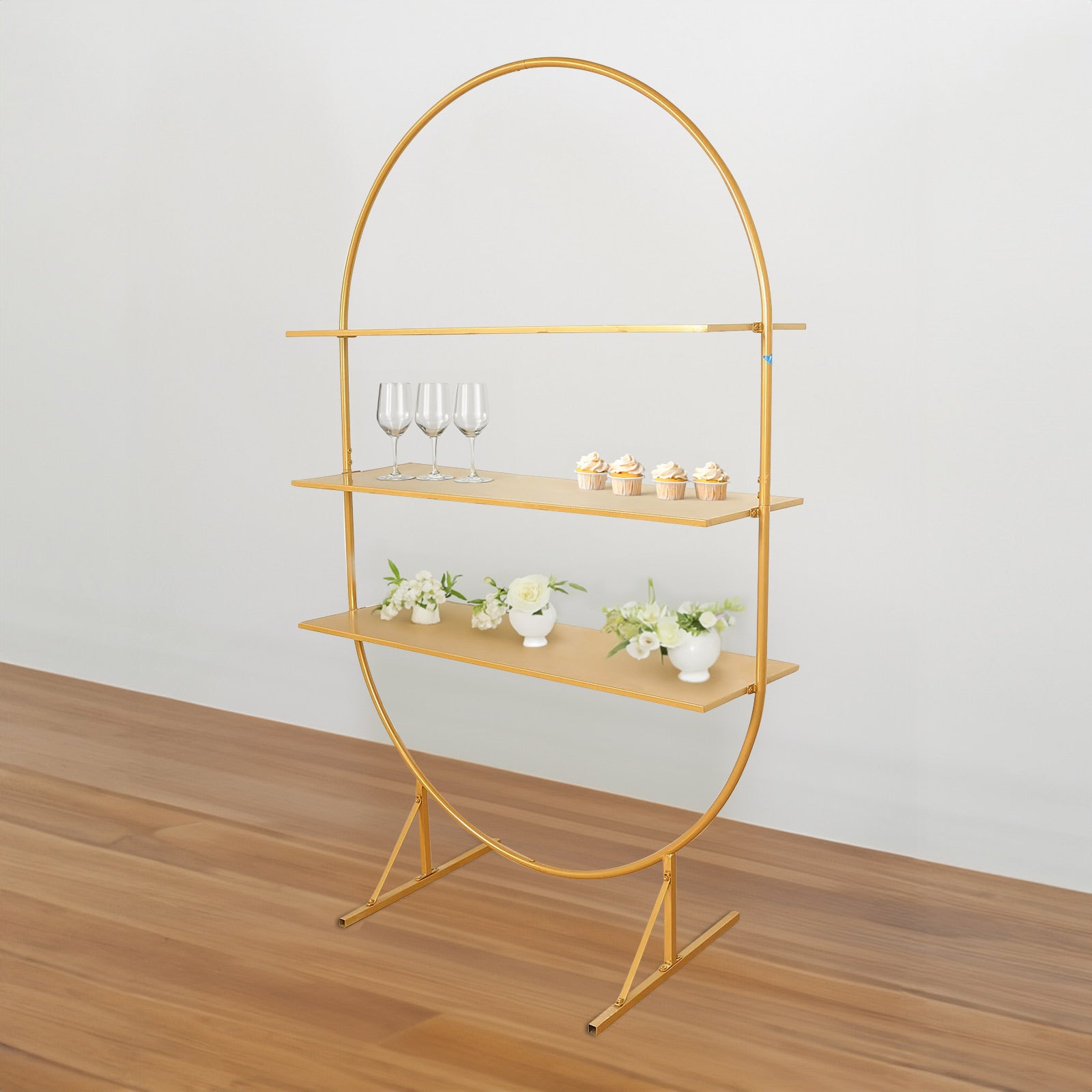 Gold 3-tier metal arch cake display stand with cupcakes and flowers.