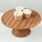 Natural rattan wicker pedestal cupcake stand with desserts on display.