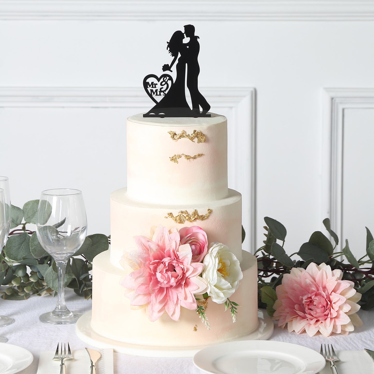 Black acrylic Mr and Mrs wedding cake topper on a decorated cake.