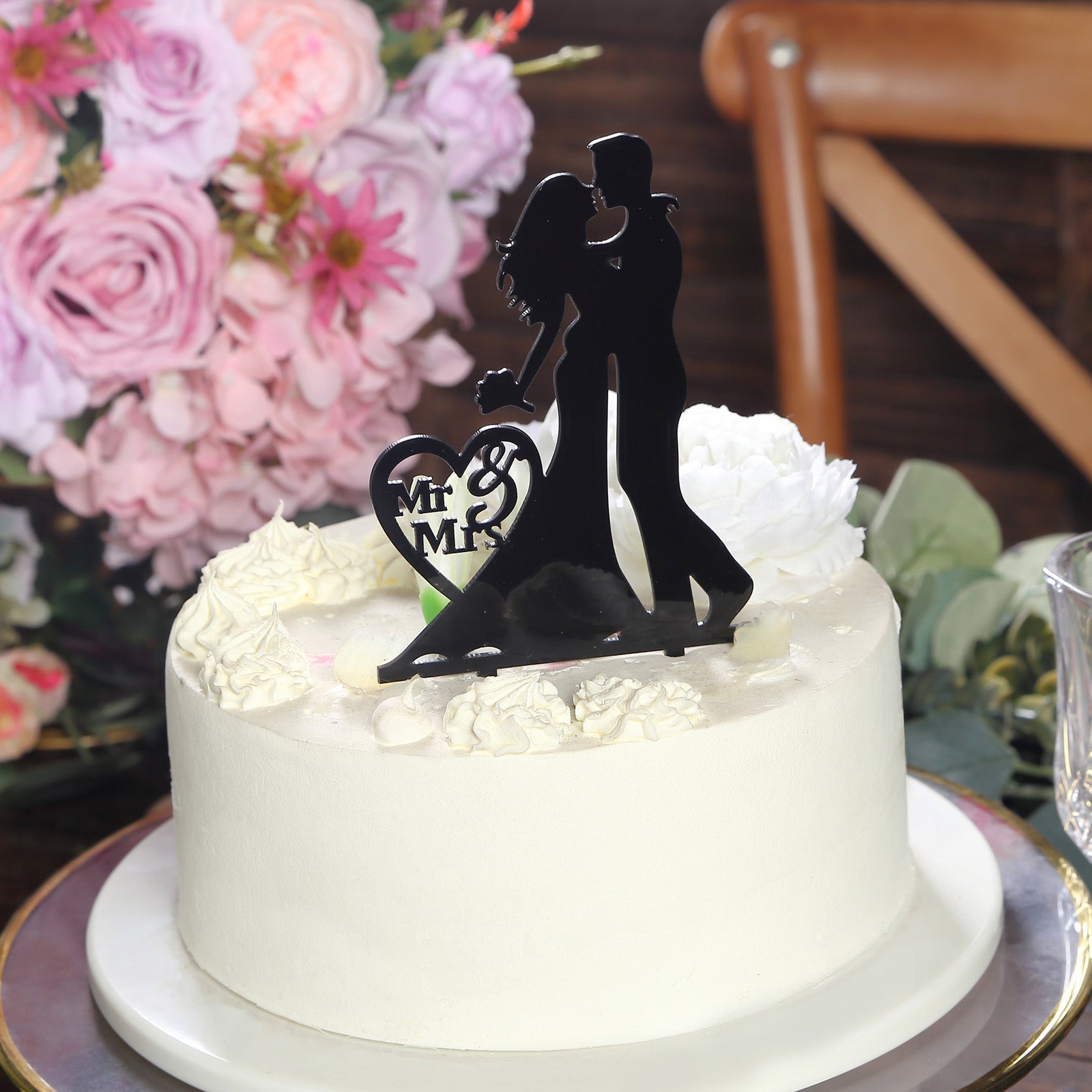 Black acrylic Mr and Mrs wedding cake topper on a white cake.