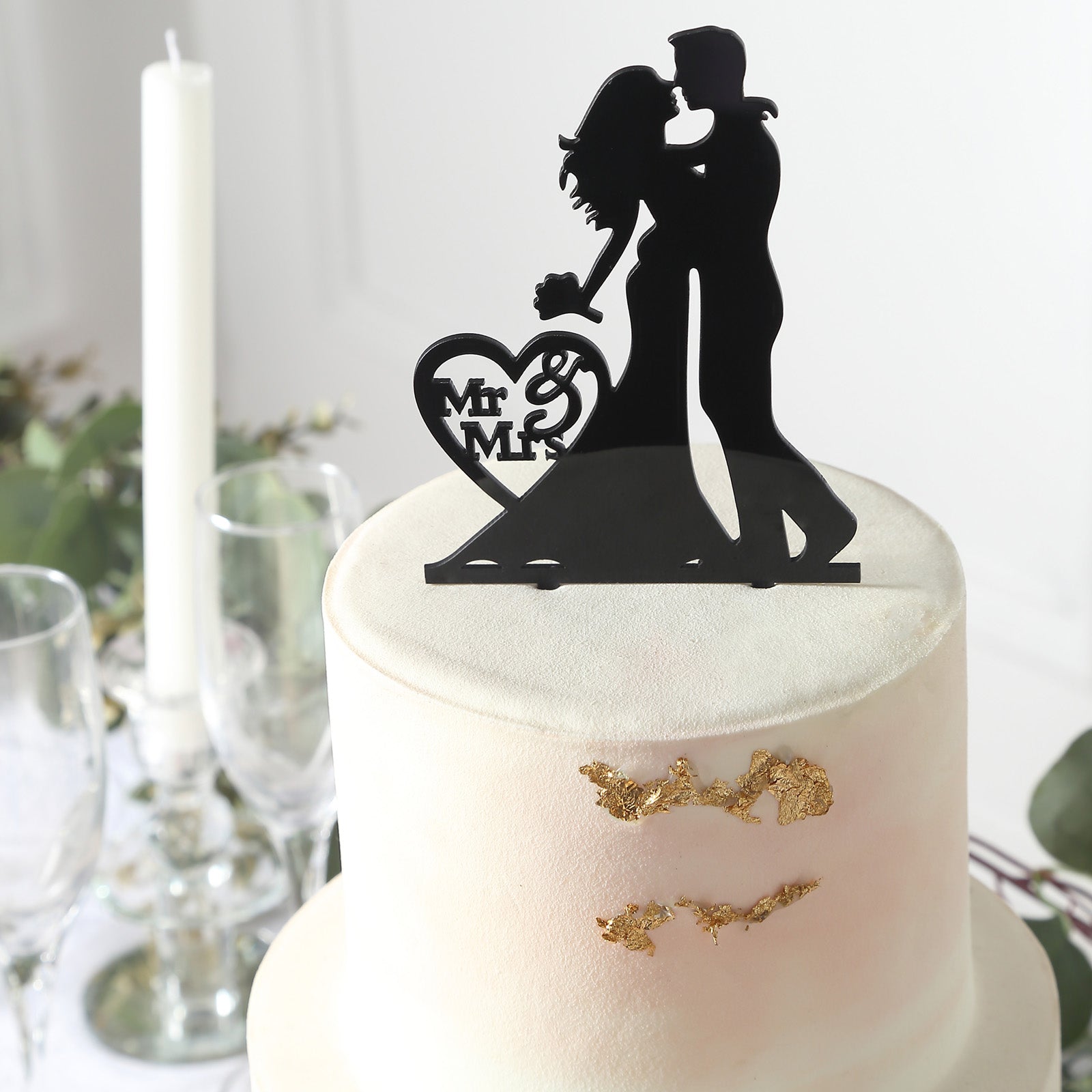 Black acrylic Mr and Mrs wedding cake topper on a pale cake.