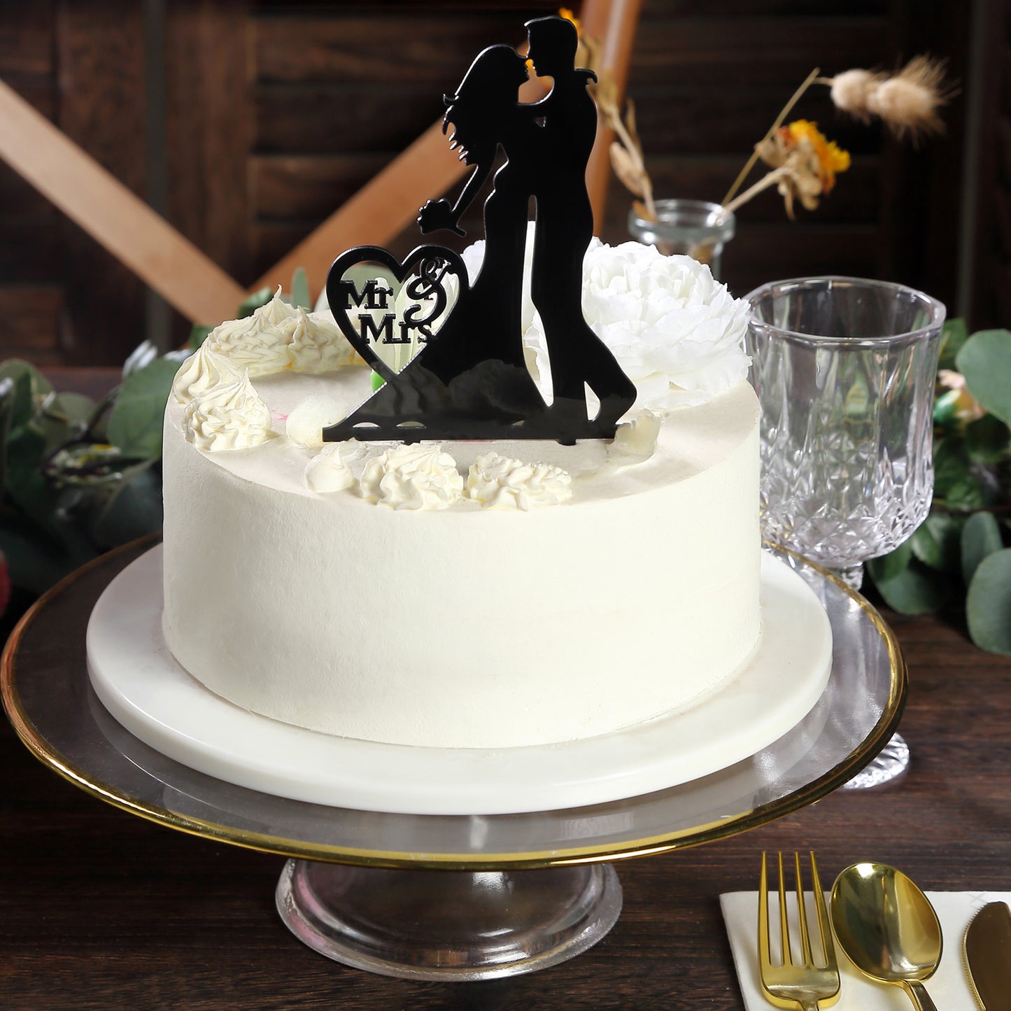 Black acrylic Mr and Mrs wedding cake topper on a white cake.