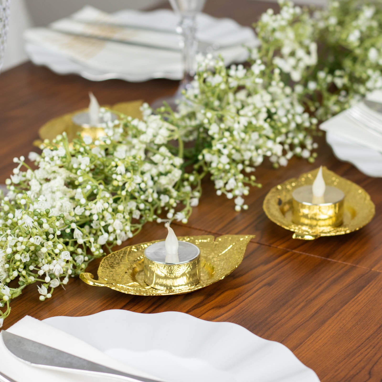 Shiny gold metal maple leaf tealight candle holders on a table setting.
