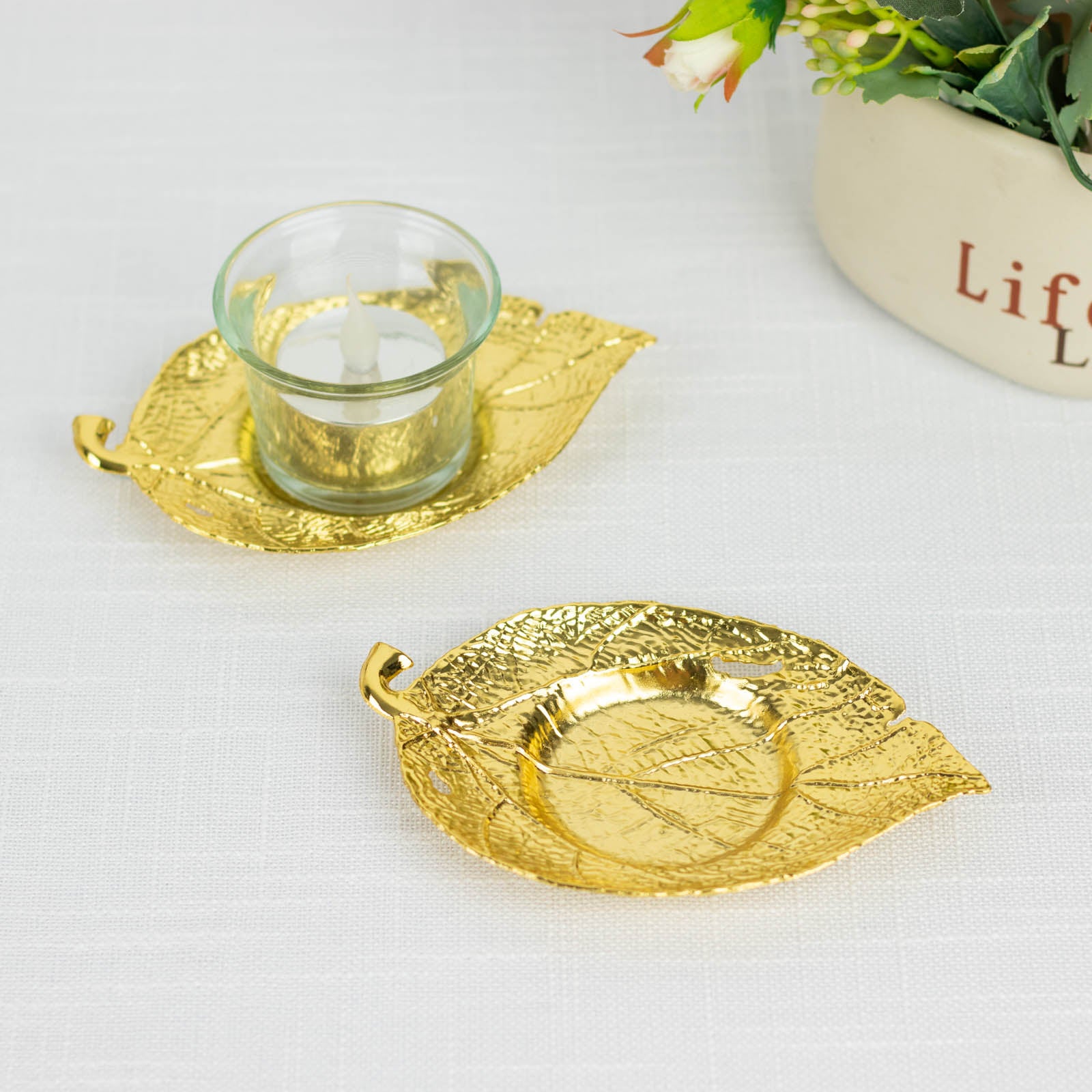Shiny gold metal maple leaf tealight candle holders on a table.