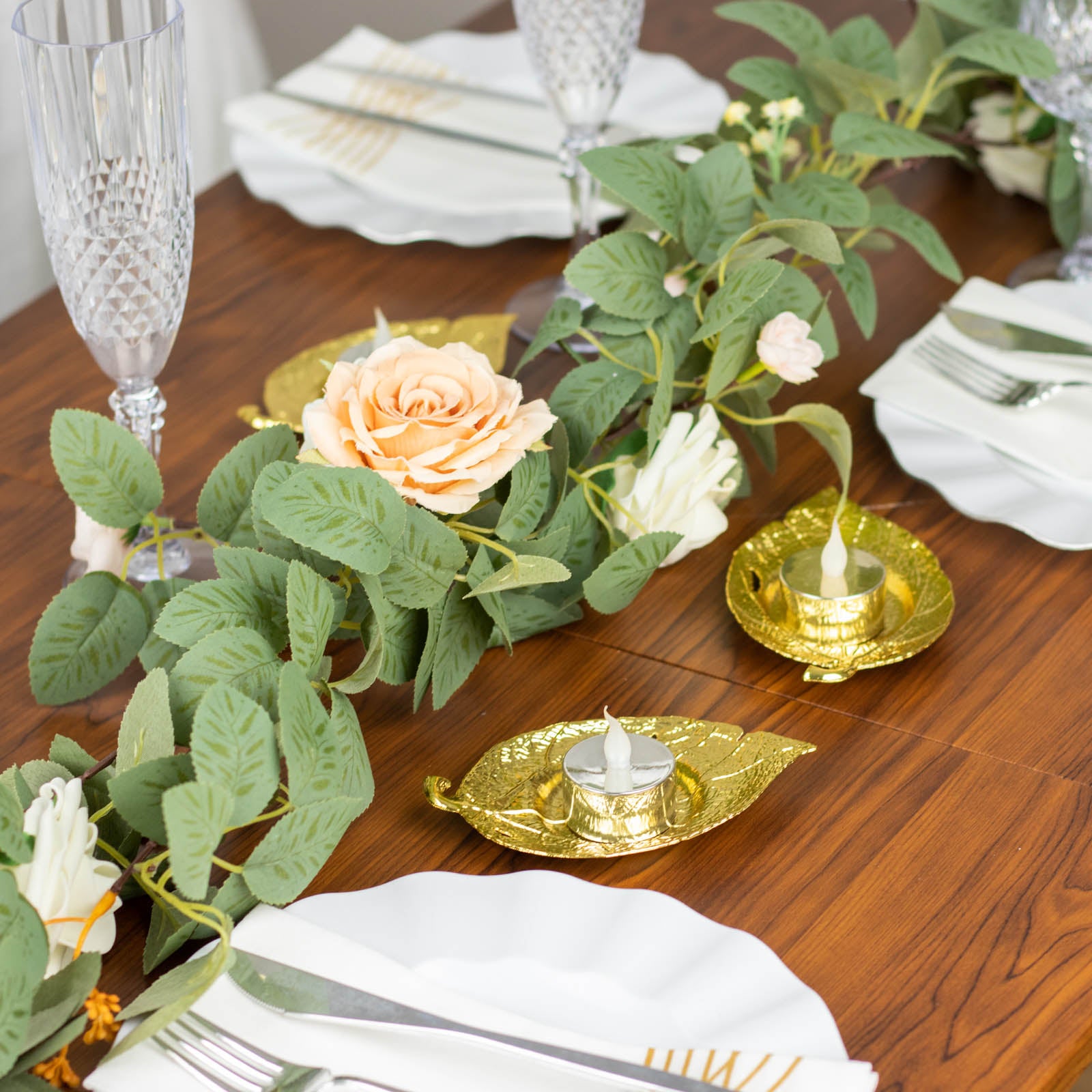 Shiny gold metal maple leaf tealight candle holders on a dining table.