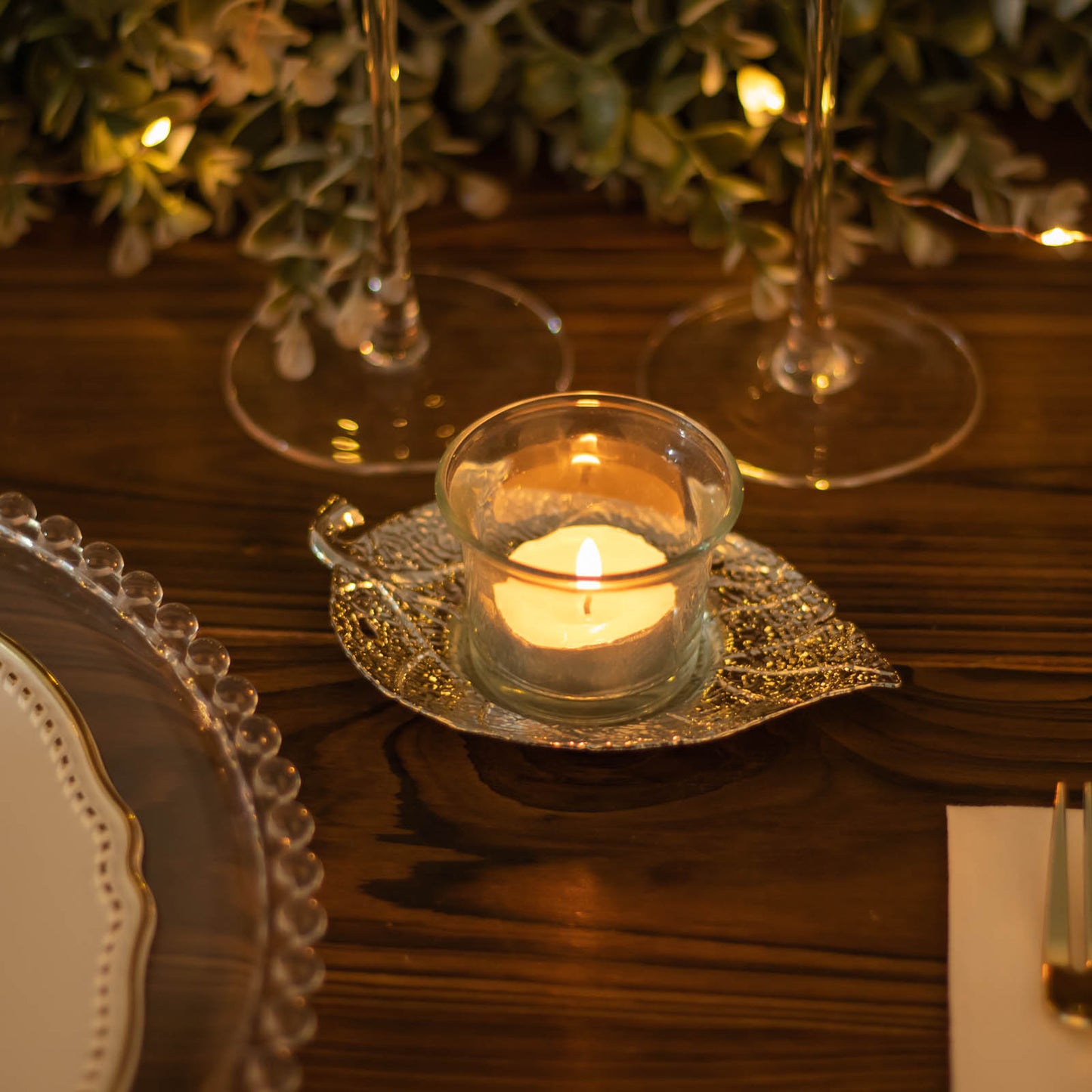 5" shiny gold metal maple leaf tealight candle holder with candle flame.