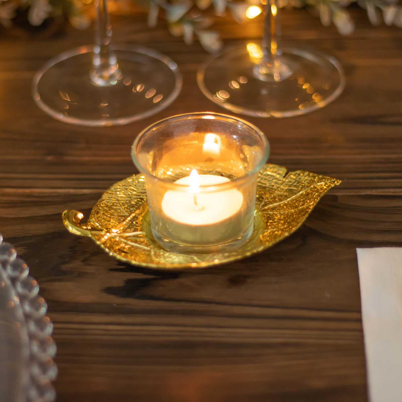 Shiny gold metal maple leaf tealight candle holder with candle.