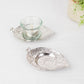 Shiny silver metal maple leaf tealight candle holders on a white surface.