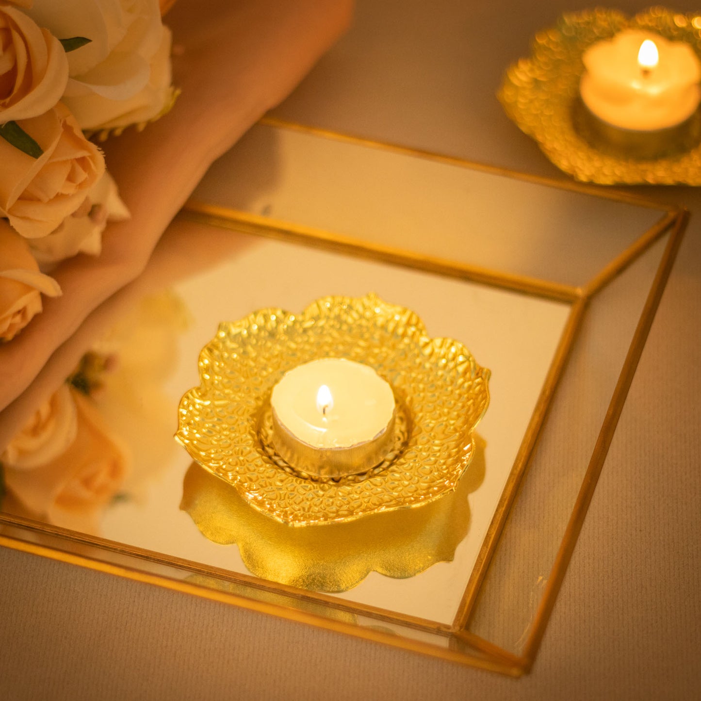 Shiny gold plum blossom tealight candle holders on a reflective surface.