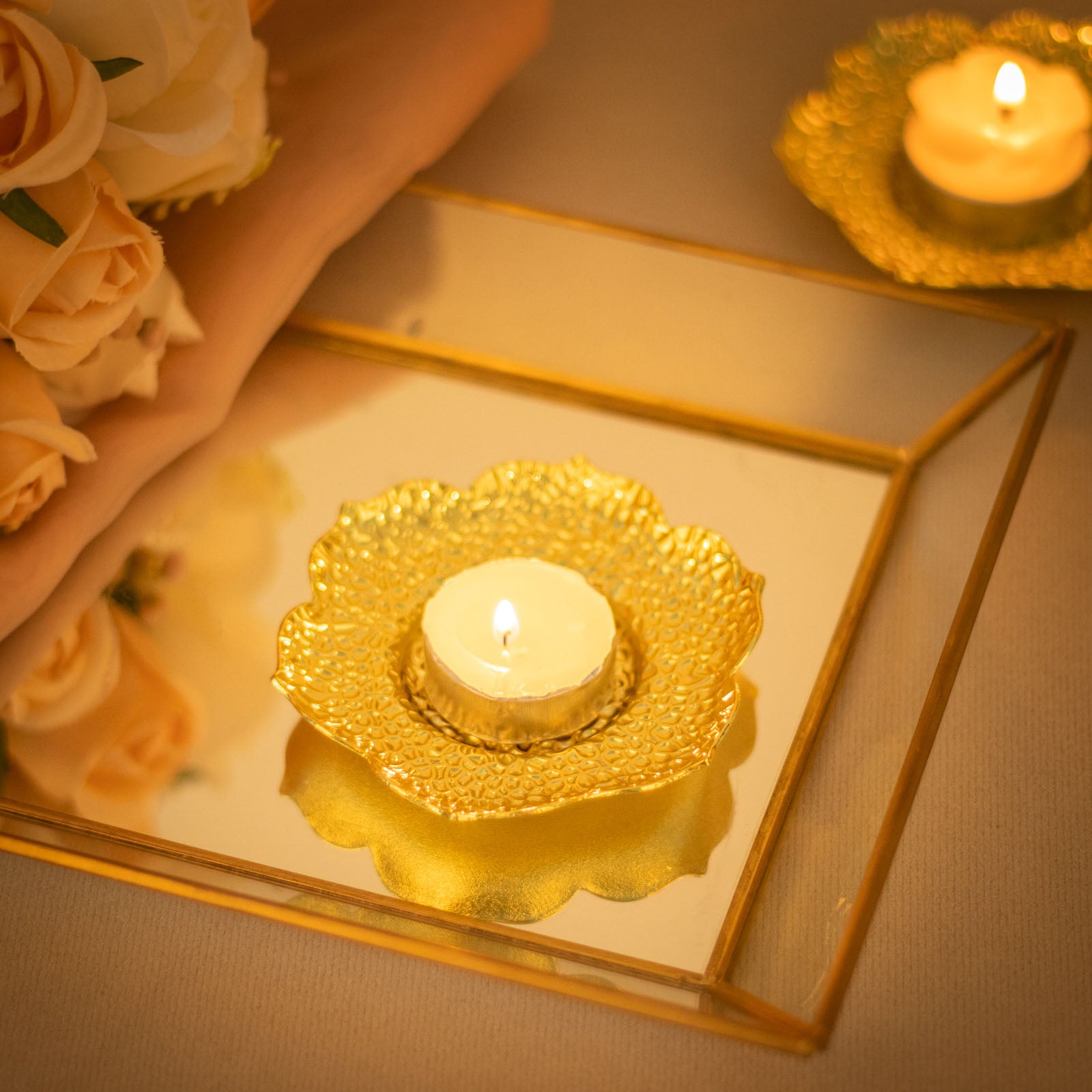 Shiny gold plum blossom tealight candle holders on a reflective surface.